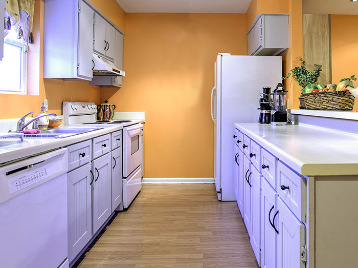 quartz kitchen countertop with white cabinets and orange walls behind